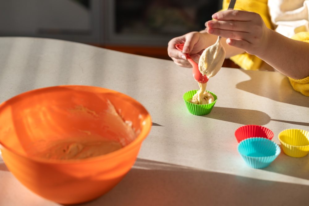 female hands spread the dough into muffin baking tins