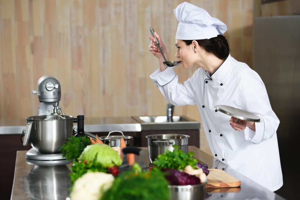 Female chef tasting dish on restaurant kitchen