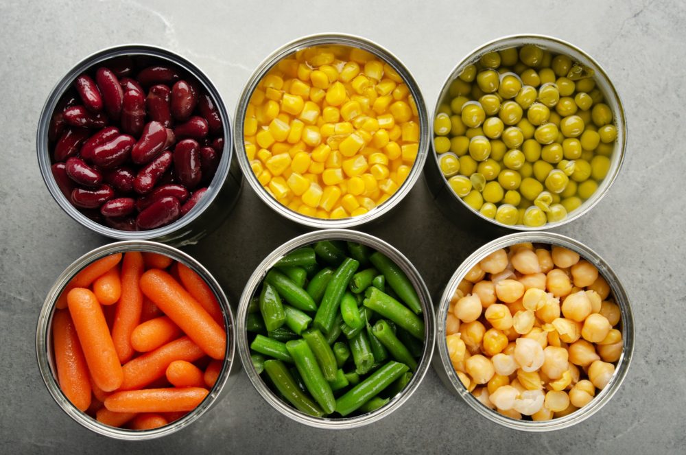 Flat lay view at canned carrots, chickpeas, kidney beans, green beans, peas and corn