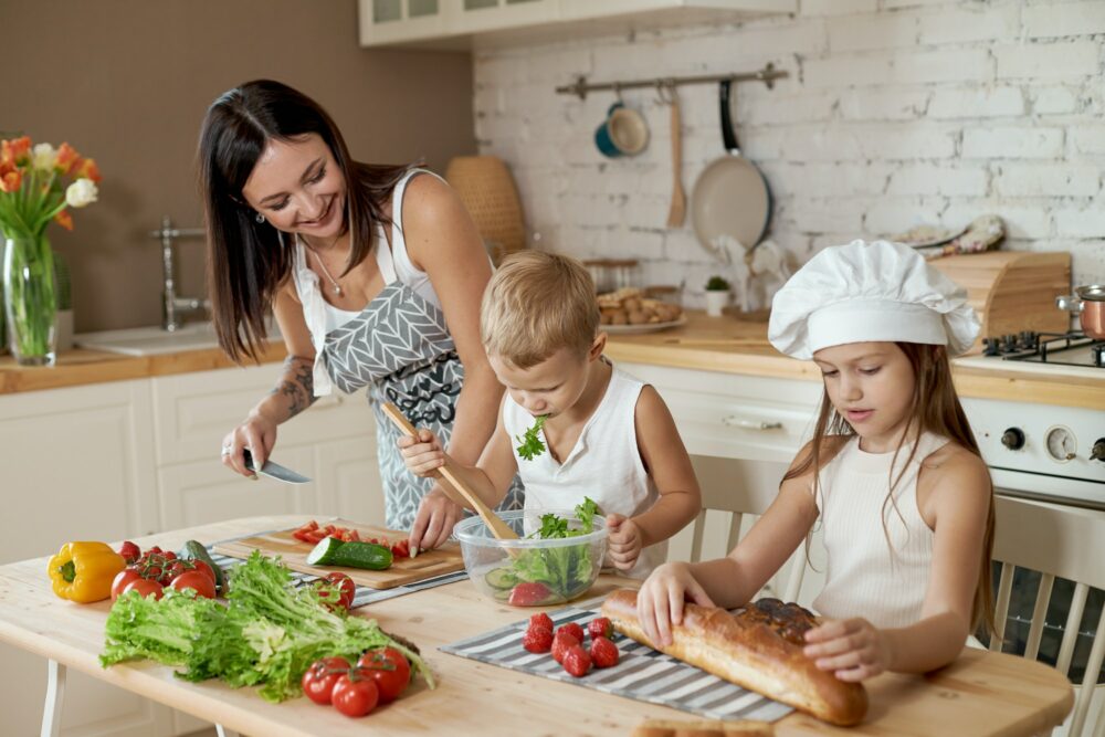Mom teaches her daughter and son to prepare a Salad of fresh vegetables. Healthy natural food