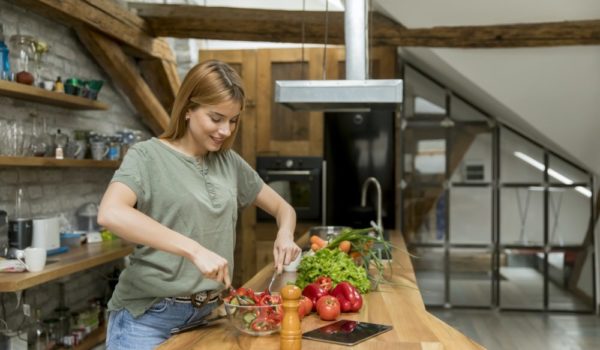 Happy young woman cooking delicious and healthy food in the loft kitchen at home